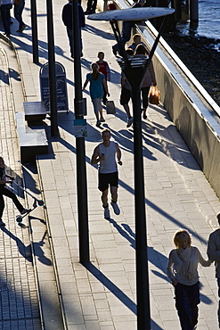 Pedestrians and jogger on Thames Path, London, England, United Kingdom