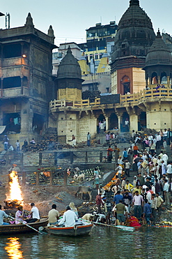 Tourists watch body bathed in River Ganges and traditional Hindu cremation on funeral pyre at Manikarnika Ghat in Holy City of Varanasi, Benares, India