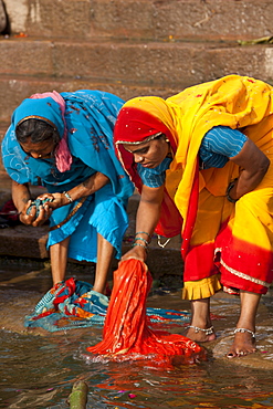 Indian Hindu pilgrims washing clothes and bathing in The Ganges River at Dashashwamedh Ghat in Holy City of Varanasi, India