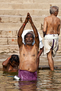 Indian Hindu man bathing and praying in the River Ganges by Kshameshwar Ghat in holy city of Varanasi, India