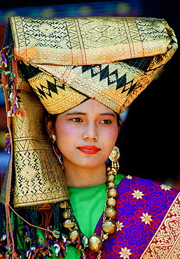 A young girl wearing an ornate gold head-dress with gold necklace and earrings in traditional style in Java, Indonesia.