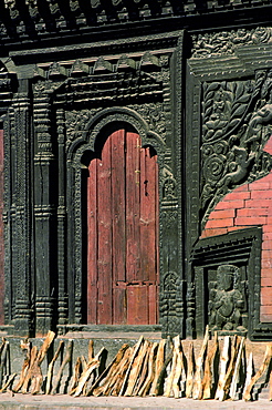 Firewood drying near ornate carved wooden doorway, Bhaktapur, Nepal