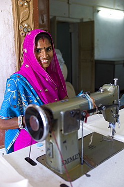 Indian woman sewing textiles at Dastkar women's craft co-operative, the Ranthambore Artisan Project, in Rajasthan, Northern India