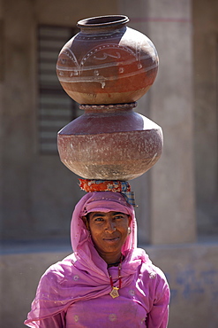 Indian woman in sari fetching water pots from well at Jawali village in Rajasthan, Northern India