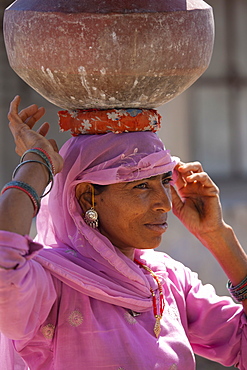 Indian woman in sari fetching water pots from well at Jawali village in Rajasthan, Northern India