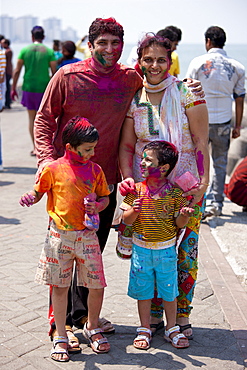 Indian family celebrating annual Hindu Holi festival of colours with powder paints at Nariman Point in Mumbai, formerly Bombay, India