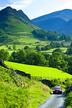 Motoring holiday tourists driving through Cumbrian mountain range near Derwentwater in Lake District National Park, UK