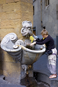 Woman washing grapes in water fountain in Florence,Tuscany, Italy