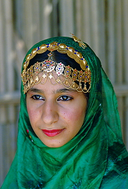 An Omani woman wearing gold jewels and a veil, Nizwa, Oman