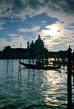 Canals of Venice at daybreak with gondolas and the Church of Santa Maria Della Salute silhouetted against the sky, Italy