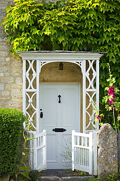 Traditional vine-covered Cotswold house with Georgian porch in The Cotswolds, Gloucestershire, UK