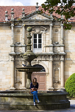 Spanish girl by fountain at Colexio de San Clemente de Pasantes in Santiago de Compostela, Galicia, Spain