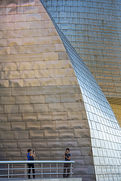 Couple taking photographs at Architect Frank Gehry's Guggenheim Museum at Bilbao, Basque country, Spain