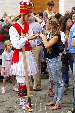 Dancer in costume chats with woman in casuals at San Fermin Fiesta at Pamplona, Navarre, Northern Spain