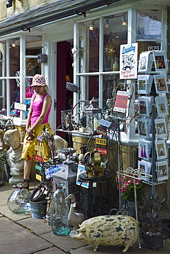 Tourist leaving curiosity shop selling souvenirs, collectibles and gift items in Chipping Campden, The Cotswolds, UK