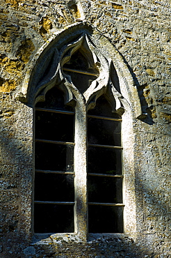 Norman style old stone window at 11th Century St Nicholas Church, Oddington, near Stow on the Wold, Gloucestershire