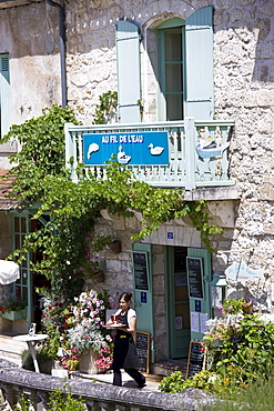 Waitress serving at French outdoor cafe in tourist town at Brantome in the Northern Dordogne, France