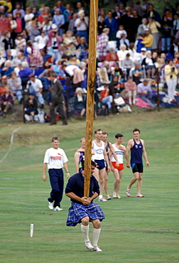 Scottish strongman in tartan kilt tossing the caber at the Braemar Royal Highland Gathering, the Braemar Games in Scotland