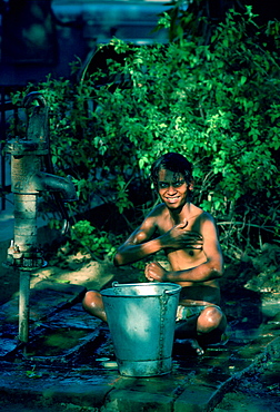 Boy washing at handpump, street scene, Delhi, India