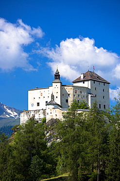 Tarasp Castle surrounded by larch forest in the Lower Engadine Valley, Switzerland, Europe