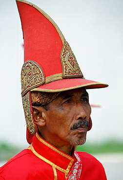 Courtier at the Sultan's Palace,Yogyakarta, Indonesia wearing a pointed hat and bright red uniform