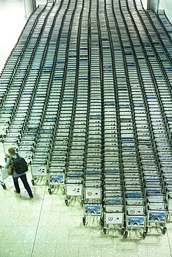 Generic shot of traveller collecting a trolley from hundreds of luggage trolleys at an airport, United Kingdom, Europe