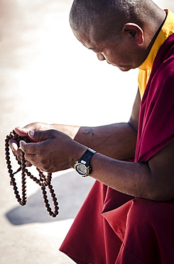 A Buddhist monk prays using a set of prayer beads (Japa Mala), Bodhnath stupa, Bodhnath, Nepal, Asia 