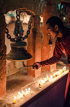 A Buddhist monk rings a prayer bell during the full moon celebrations, Bodhnath stupa, Bodhnath, Nepal, Asia 