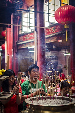 A man and women light incense sticks and pray during Chinese New Year celebrations, Sze Ya Temple, Chinatown, Kuala Lumpur, Malaysia, Southeast Asia, Asia