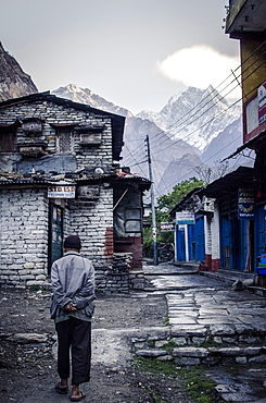 A man walks through Tatopani, with Nilgiri Peak, 7061m, in the background, Annapurna Conservation Area, Nepal, Himalayas, Asia 