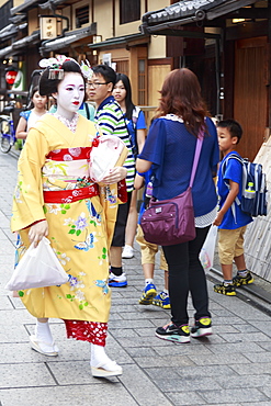 Maiko, apprentice geisha, walks to evening appointment through tourist crowd, Hanami-koji street, Gion, Kyoto, Japan, Asia