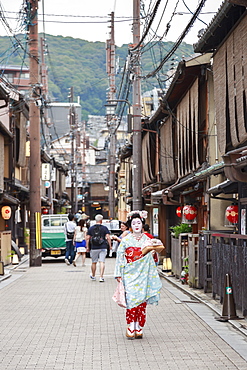 Maiko, apprentice geisha, walks to evening appointment past traditional wooden buildings, Gion, Kyoto, Japan, Asia