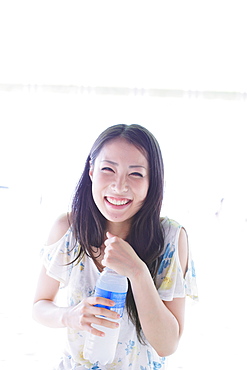 Japanese woman holding a bottle of water and smiling at camera