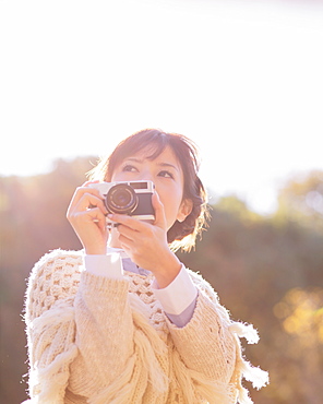 Portrait of a Japanese woman in a white cardigan holding an old camera