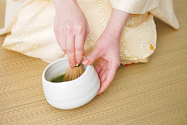 Woman Whisking Herbal Tea in Bowl