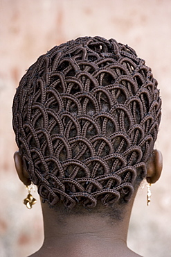 A woman's head with braided patterned hair and earrings, Benin, Africa