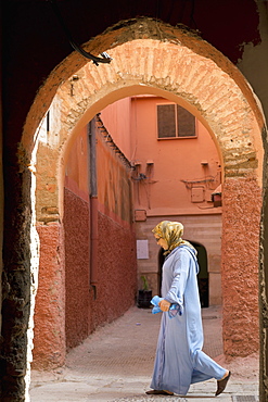 A Moroccan woman in front of an archway in the alleys of Marrakesh, Morocco