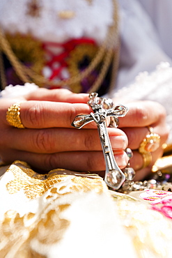 Person holding cross at Sant'Efisio procession, Pula village, Sardinia, Italy