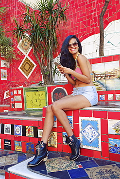 Young Brazilian woman, 20 to 29 years old, using her mobile phone on the Selaron steps in Lapa, Central Rio de Janeiro, Brazil, South America