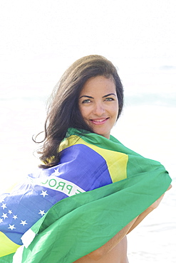 Young Brazilian woman 20 to 29 years old with a Brazilian flag beach wrap on a beach, Rio de Janeiro, Brazil, South America