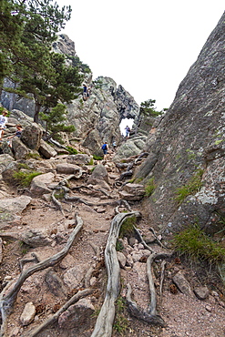 Hikers proceed in the rocky canyon Col de Bavella (Pass of Bavella), Solenzara, Southern Corsica, France, Europe