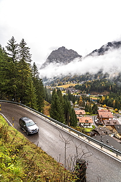 Car travelling on mountain road towards the village of Canazei in autumn, Dolomites, Val di Fassa, Trentino-Alto Adige, Italy, Europe