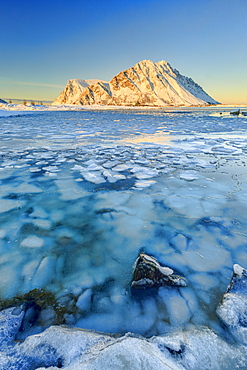 Views of the mountains of Gymsoya (Gimsoya) from Smorten reflected in the clear sea still partially frozen, Lofoten Islands, Arctic, Norway, Scandinavia, Europe