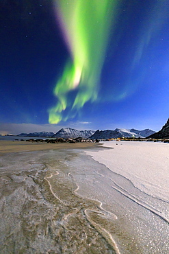 The Northern Lights (aurora borealis) light up the sky and the beach of the cold sea of Gymsoyand (Gimsoy), Lofoten Islands, Arctic, Norway, Scandinavia, Europe