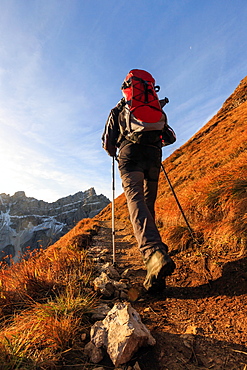 Hiker proceeds toward the group Forcella De Furcia at sunrise, Funes Valley, South Tyrol, Dolomites, Italy, Europe