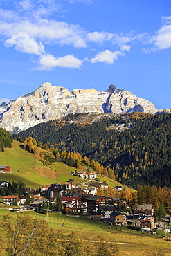 Colourful woods frame the village and the high peaks in autumn, Gardena Valley, South Tyrol, Trentino-Alto Adige, Italy, Europe