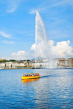 Yellow water taxi ???Mouettes genevoises??? on the calm waters of Lake Geneva with tourist attraction Jet d'eau in the background