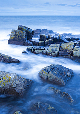 Rocks and Summer Isles in the background during dramatic blue lighting at dusk on the shores of northwest Scotland, Highland, Scotland, United Kingdom, Europe