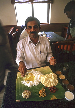 India - food: man eating vegetarian meal from a banana leaf in a restuarant of trivandrum, kerala