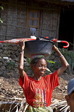 East timor. Woman carrying plastic bowl and umbrella, kefua village, oecussi-ambeno